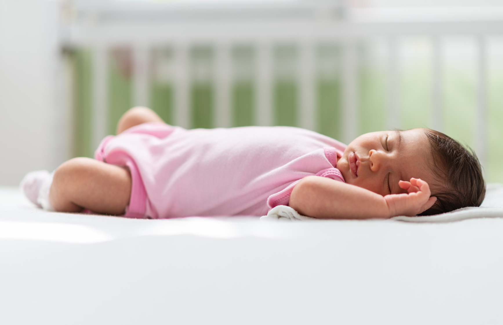 Un bébé dort sur le dos dans un lit d’enfant. Il n’y a rien d’autre dans le lit avec le nourrisson qui dort paisiblement.